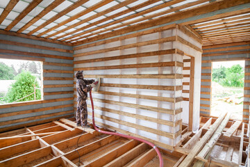 Blowing ecowool into a wall in a frame house under construction
