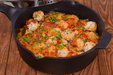 Stewed rice meatballs in deep frying pan on rustic table