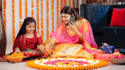 Diwali rangoli - Mother and daughter making flower art   Auspicious Hindu festival. A young girl-child in ethnic wear decorating a floral Rangoli with flower petals - Diwali decorations  festive se...