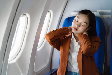 Tired asian woman with headache feeling sick while sitting in the airplane , Passengers near the...