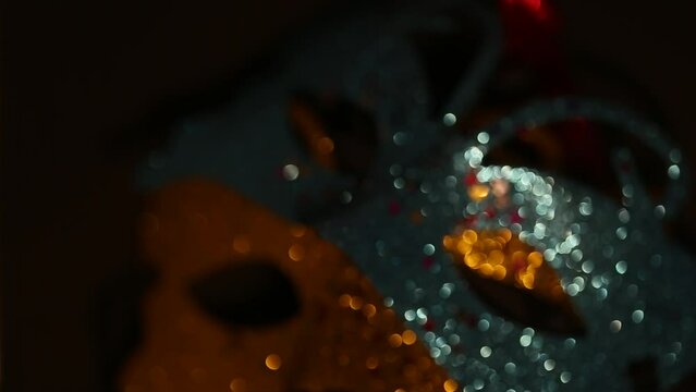 Blue and gold shiny carnival masquerade fantasy mask with small colorful stars under light in dark. Two luxury traditional venetian masks on dark background illuminated and sparkles from the darkness