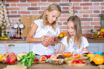 Two little girls in the kitchen with fresh vegetables. Healthy food concept. Happy sisters.