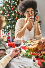 cheerful african american woman talking to her relatives drinking wine with Christmas tree backdrop