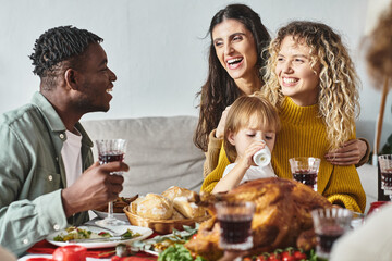 cheerful lgbt couple surrounded by relatives holding their daughter in hands, Christmas celebration