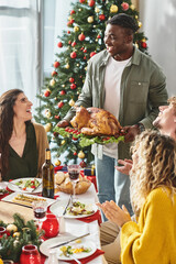 big multicultural family enjoying Christmas feast with wine and turkey and smiling sincerely
