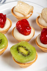 Fruit tartlets. Strawberry, banana and kiwi tartlets on a plate. snack sweet food. Close up
