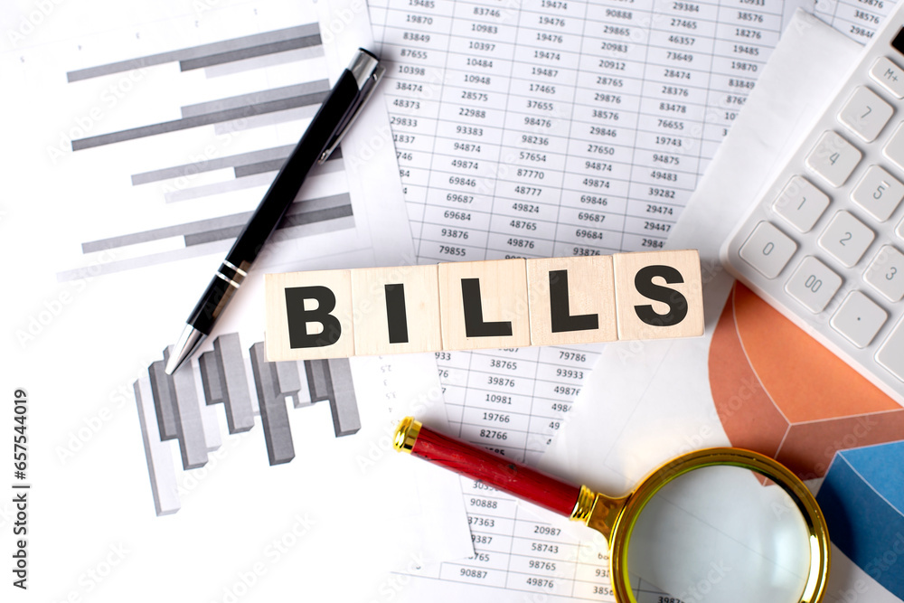 Poster bills text on wooden block on graph background with pen and magnifier