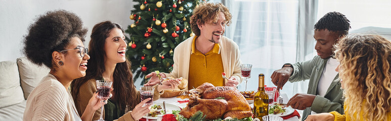 big multiethnic family smiling and eating festive lunch with Christmas tree on background, banner