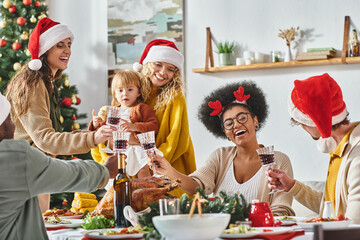 big multiethnic joyful family clinking their glasses at festive table wearing Santa hats, Christmas