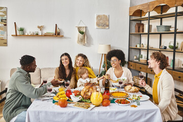 joyful multiethnic friends and family sharing tasty dinner while celebrating Thanksgiving together