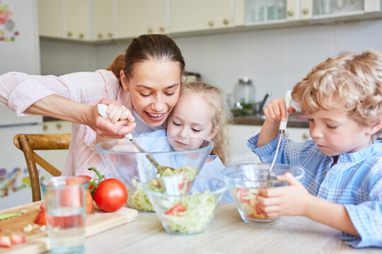 Mother and daughter mixing salad in kitchen