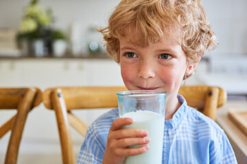Thoughtful boy holding glass of milk at home