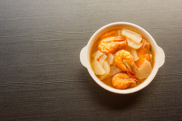 Shrimp curry with radish in a bowl on a black table, top view