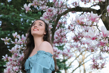 Beautiful woman near blossoming magnolia tree on spring day