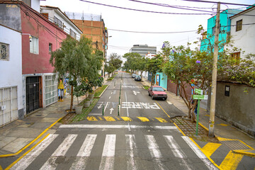 Casas, rua com lombada e carros estacionados em Lima.