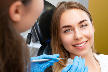 Brown-haired young woman preparing for dental procedure with dentist at private clinic appointment. Woman wants to cure teeth and have even smile