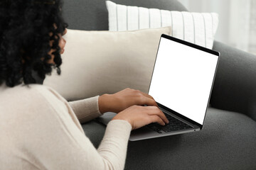 Naklejka premium Woman using laptop on sofa at home, closeup