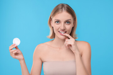 Young woman with cotton pad on light blue background