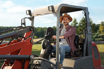 Naklejka premium Smiling farmer driving loader outdoors. Agriculture equipment