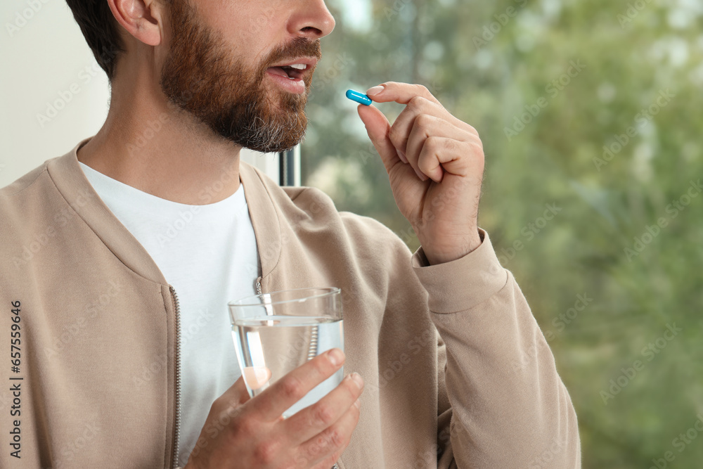 Canvas Prints Man with glass of water taking pill indoors, closeup. Space for text