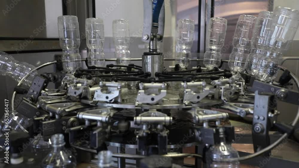 Poster plastic bottles within a factory undergo a cleansing and purification process as they rotate on auto