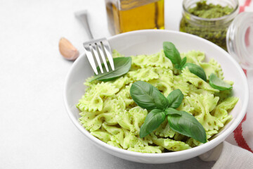 Delicious pasta with pesto sauce and basil served on light table, closeup. Space for text