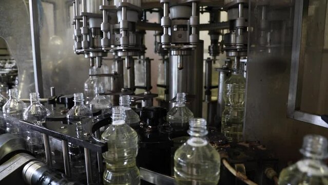 Plastic bottles rotate on an automated machine as they are filled with fresh vinegar at a factory processing plant.