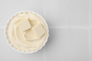 Delicious tofu sauce in bowl on white tiled table, top view. Space for text