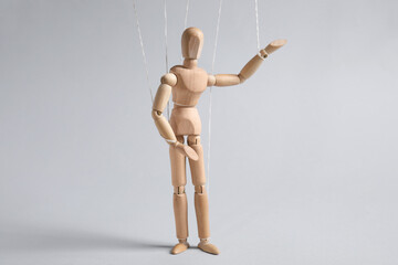 One wooden puppet with strings on light grey background