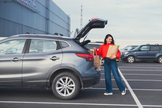 smiling woman put bags in car trunk