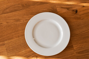 Ceramic white flat plate for food on wooden table top view
