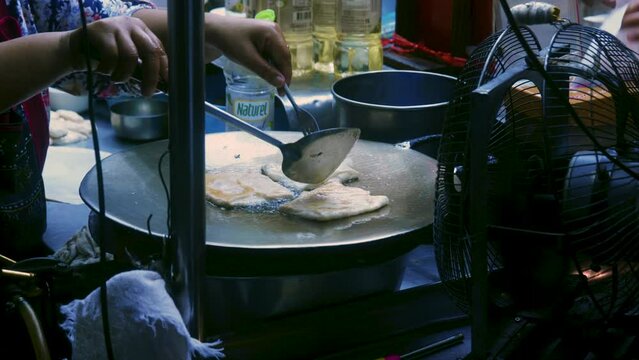 4K Cinematic cooking footage of a Thai chef preparing a traditionnal Thai dessert called Roti in a street market in Thailand
