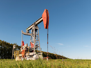 Operating oil and gas well in oil field, profiled against the blue sky