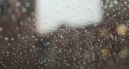 Raindrops on windowpane during a rainy day, capturing the tranquility and melancholy of nature's...