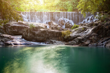 Obraz premium Small waterfall with water splashing and tumbling over the rocks in the forest on a bright sunny,kra-ang waterfall