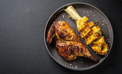 Chinese, Asian cuisine. half of fried chicken in spicy sauce, fried pineapple, dish on a plate on a black background, top view
