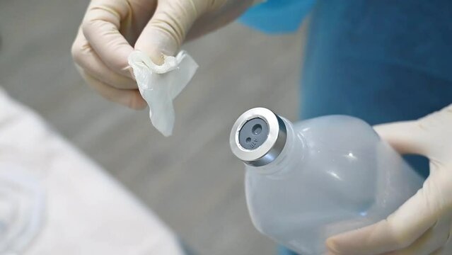 Dental assistant wiping bottled saline with wine gauze in dental implant surgery