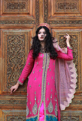Young brunette woman in uzbek or indian traditional dress on background of ancient national...