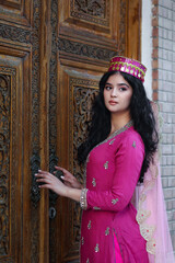 Young brunette woman in uzbek or indian traditional dress on background of ancient national...