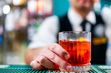 man bartender hand holding negroni cocktail in bar