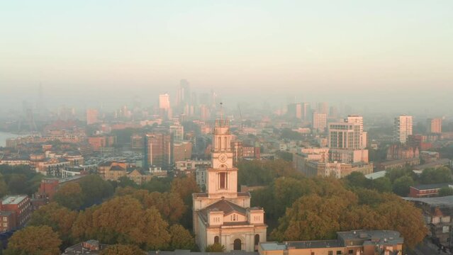 Close up aerial shot of St Annes Church Limehouse at sunrise with central London skyline in the background
