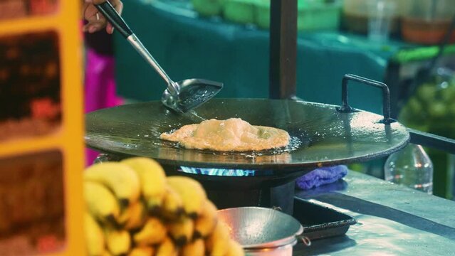 4K Cinematic cooking footage of a Thai chef preparing a traditionnal Thai dessert called Roti in a street market in Thailand