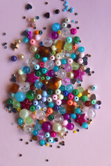 Various colorful beads on bright pink background. Top view.