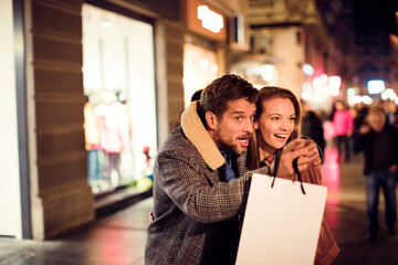 Young couple shopping and walking downtown in the city at night