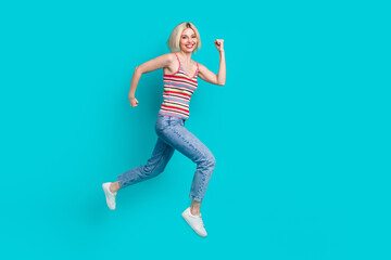 Fototapeta na wymiar Full length photo of cute excited lady wear striped singlet jumping high empty space isolated turquoise color background