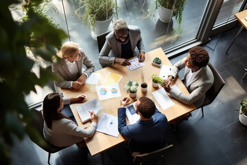 Top view of business people brainstorming at desk, analyzing financial reports and data in modern office.