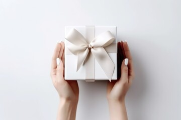 White gift for wedding in female hands on white background. Monther day. View from above. Greeting card. Minimalism.