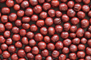 Horse chestnut. Autumn background, chestnuts on a wooden background, top view. Chestnuts are laid out in one layer on the table. Texture. Scattered horse chestnuts on a brown background