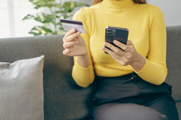 happy woman Credit card and phone and laptop on sofa, online shopping Ecommerce and payments made easy Asian man in China typing bank information