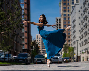 Beautiful Asian ballerina dancing outdoors. Urban landscape.